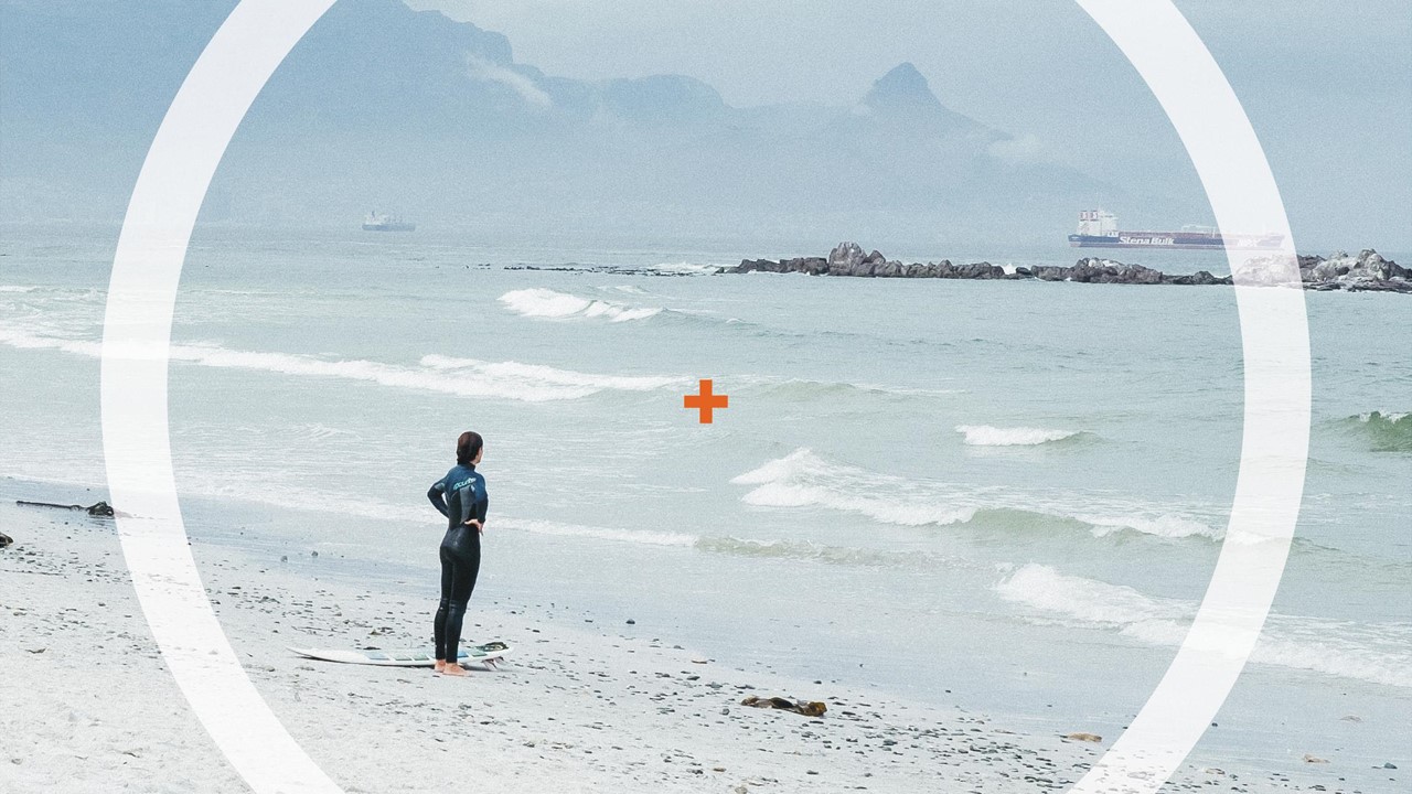 Picture of a women standing at the beach and looking out onto the sea.